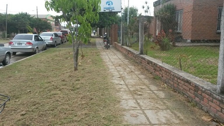 La vereda de Aguas de Clorinda con el césped cortito. 